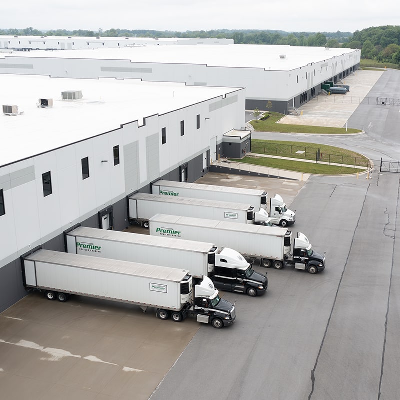 lsl-trucks-at-docks-min flyover view of large storage facilities with trailer trucks parked outside